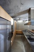 Designer kitchen with stainless steel surfaces in concrete house