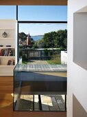 Glass balustrade around aperture in floor in front of floor-to-ceiling windows with superb view