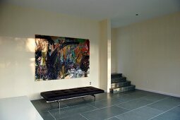 Black couch on large, grey tiles in minimalist foyer