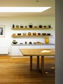 Shelves with ceramic bowls and teapots behind dining table