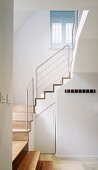 White-painted stairwell with wooden stairs and stainless steel balustrade