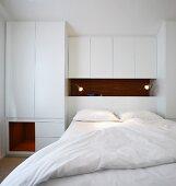 Schlafzimmer mit Doppelbett vor weißem Einbauschrank im Designerstil