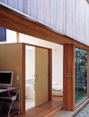 Modern house with open folding terrace door and view of wooden, cubist bathroom installation