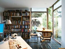 Study with bookcase and glass walls with view of garden