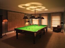 Darkened billiard room with two leather armchairs