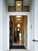 Open front door with view into narrow hallway with lantern pendant lamps