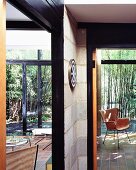 Modern house - view past unrendered concrete block walls with black wooden frames to bamboo garden