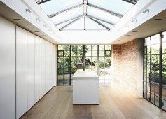 A modern skylight and historic windows in a simple kitchen with walls of handle-less cupboards and an island counter