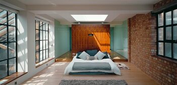 A sunlit loft bedroom with an en suite bathroom behind the double bed