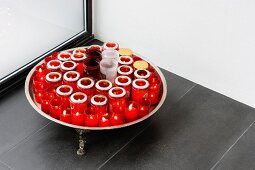 Tray with red tea light holders on grey tiled floor