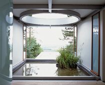 Loggia in contemporary building with plant pots in pool in front of garden