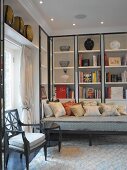 Classic, modern seating corner with vases and books in fitted shelving