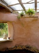 Clay house with organic lines, simple skylight structure and Buddha statue in frameless window aperture