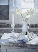 weiße Gedeck, silberne Windlichter, Kerze und Amaryllis auf einem Holztisch