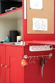 Red tool cabinet with pinboard, attached workbench, multiway power strip and hook rail