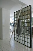 Slanted metal support as funky coat rack in front of glass brick partition
