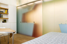 Offener Schlaf- und Essbereich und Designer-Küche hinter Milchglaswand in einem Appartement