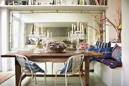 Second-hand chic - old dining table with crystal candelabras in front of a large mirror with retro metal chairs and colorful pillows