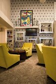 Groups of armchairs with yellow upholstery in lounge with ornate, retro-style black and white wallpaper