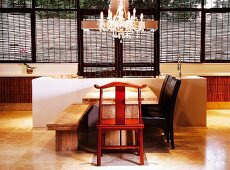 Moderne Designerküche mit schlichtem Sitzplatz vor dem Küchenblock, Kronleuchter und ausgefallener Holzstuhl als verspielte Elemente