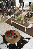 Open living room with a animal skin rug and black chandelier; underneath a large bouquet of roses on a round table