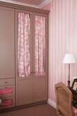 Clothes closet with door drapes - their color enhances the striped pattern of the wallpaper