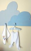Dolls' clothes on coathanger hanging on wooden pegboard in the shape of a cloud