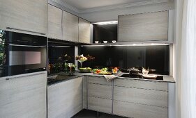 Moderne Einbauküche mit grauen Schrankfronten & schwarzen Arbeitsplatten und Rückwänden
