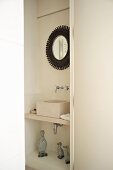Niche in bathroom containing modern wash basin and framed mirror