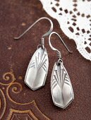 Hand made, silver earrings with embossed pattern on a leather surface