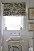Wash basin on top of antique-style cabinet below window; Roman blind printed with Chinese motifs