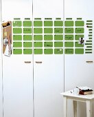 Kalender aus grünen Magnettafeln an weißer Schrankfront