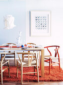 Table, designer chairs, pendant lamp with paper lampshade and wool rug in dining room