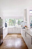 White designer kitchen with large, light brown floor tiles