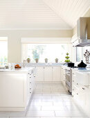 White kitchen with central kitchen island below sloping ceiling