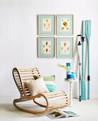 Rocking chair made from wooden slats and side table in front of blue wooden paddles leaning on wall next to gallery of pictures