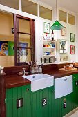 Retro kitchen with wooden worksurface and green-painted base units on interior wall with transom windows