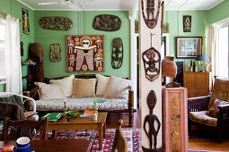 Cosy living room with antique furniture and African woodcarvings on green-painted walls