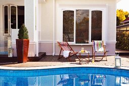 Relaxing by the pool - deckchairs and side table on side of pool in front of Mediterranean villa