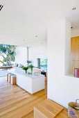 Bright, designer, contemporary kitchen-dining room with white kitchen island and open, panoramic glass wall