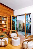 Unusual wicker chairs and small side table in front of open terrace doors in modern setting