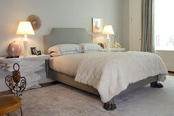 Nachtische in Bruchstein-Optik neben französischem Bett mit Wandhalterung und Klauenfüssen in postmodernem Schlafzimmer
