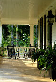 Veranda of elegant country house with dark wooden rocking chairs