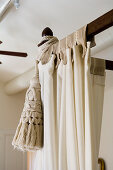 Skilfully made curtains and cream tassel on dark wood four-poster frame