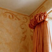 Corner of room with ornate motifs on wall and curtain