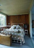 Vintage bed with white-painted metal frame in rustic bedroom