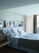 Bett mit Tagesdecke im Landhauslook vor gemauerter Ablage mit Bildern