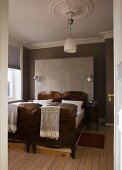 Antique twin beds standing next to one another against grey-painted walls with stucco frieze
