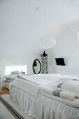 Pale, Scandinavian-style attic bedroom with spherical pendant lamp above bed