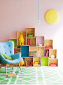 Light blue, 50s retro armchair in front of DIY shelving made from wooden crates of various sizes